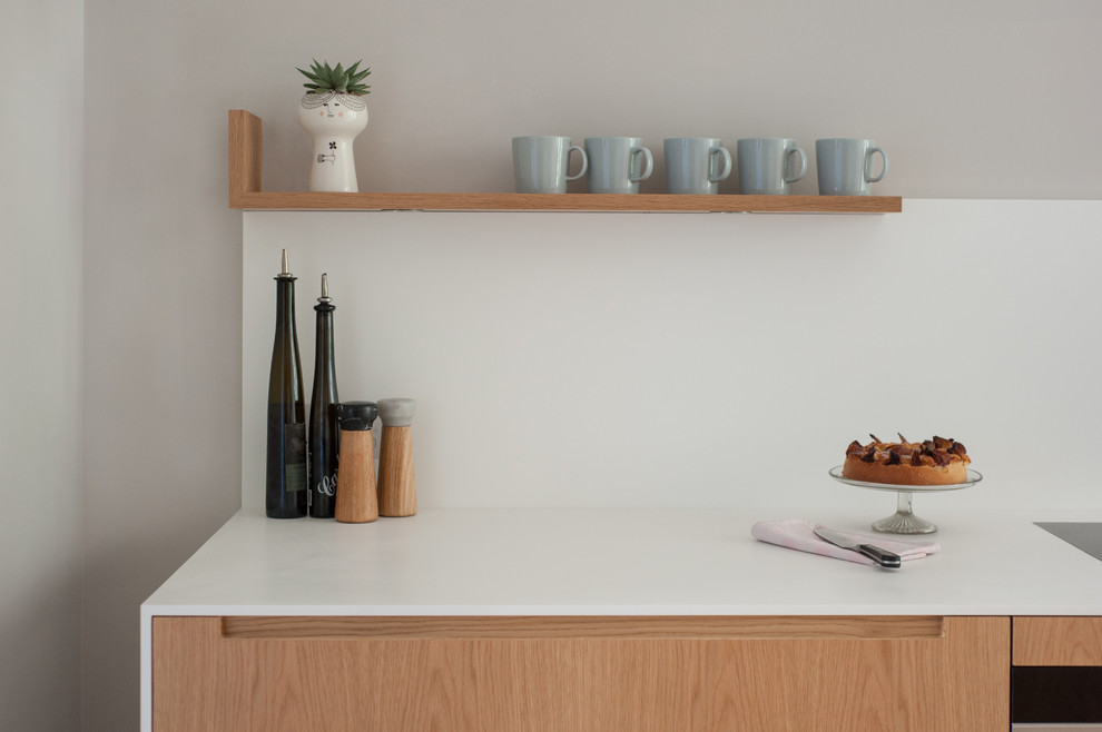 Offene, Zweizeilige, Mittelgroße Moderne Küche mit integriertem Waschbecken, Mineralwerkstoff-Arbeitsplatte, Küchenrückwand in Weiß und hellem Holzboden in London