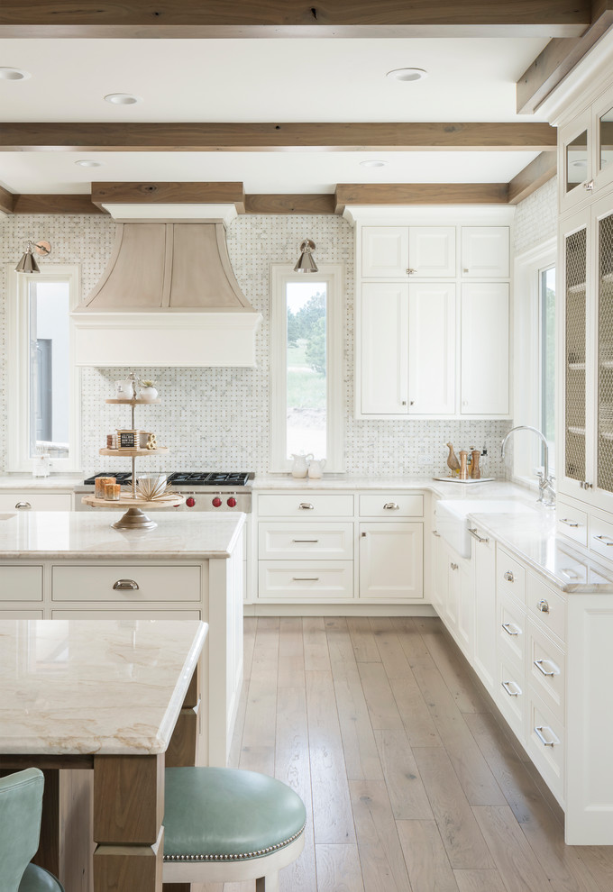 Kitchen - transitional l-shaped light wood floor and beige floor kitchen idea in Denver with a farmhouse sink, recessed-panel cabinets, white cabinets, white backsplash, mosaic tile backsplash, two islands and beige countertops