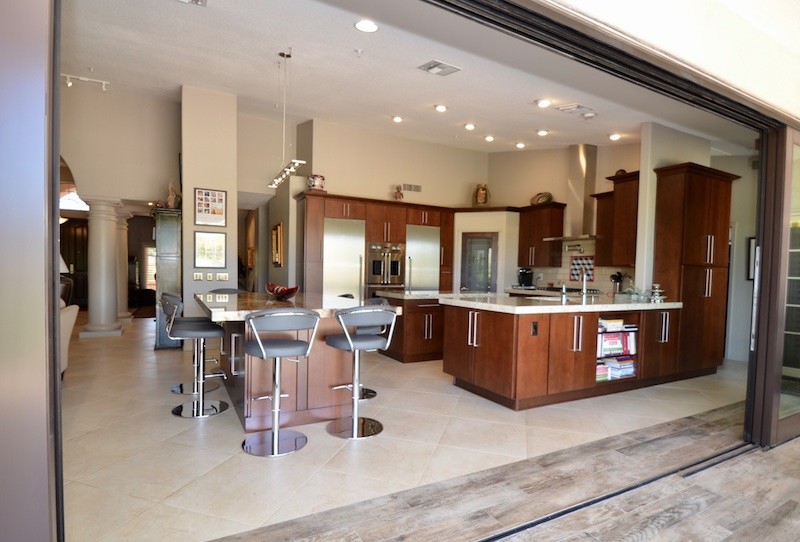 Foto på ett mellanstort funkis kök, med en undermonterad diskho, släta luckor, skåp i mellenmörkt trä, granitbänkskiva, beige stänkskydd, rostfria vitvaror och en köksö