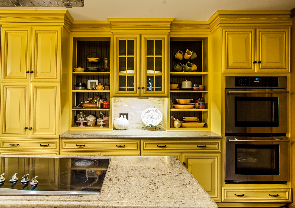 Exempel på ett avskilt, mellanstort lantligt l-kök, med en undermonterad diskho, luckor med profilerade fronter, gula skåp, bänkskiva i kvarts, beige stänkskydd, stänkskydd i stenkakel, rostfria vitvaror, mellanmörkt trägolv, en köksö och brunt golv