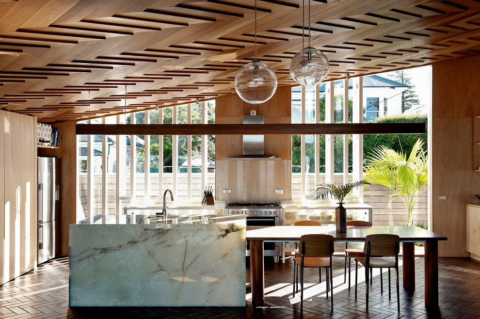 Стильный дизайн: кухня в современном стиле с обеденным столом, стеклянными фасадами, фартуком из стекла, техникой из нержавеющей стали, полом из терракотовой плитки и островом - последний тренд