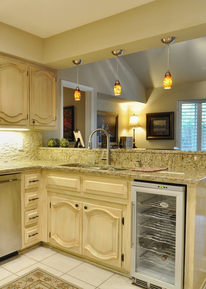 Klassisk inredning av ett mellanstort kök, med en undermonterad diskho, skåp i slitet trä, granitbänkskiva, beige stänkskydd, stänkskydd i stenkakel och rostfria vitvaror