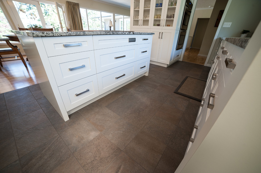 Mid-sized transitional u-shaped ceramic tile and brown floor kitchen pantry photo in Vancouver with shaker cabinets, white cabinets, granite countertops, multicolored backsplash, stone slab backsplash, stainless steel appliances, an island and an undermount sink