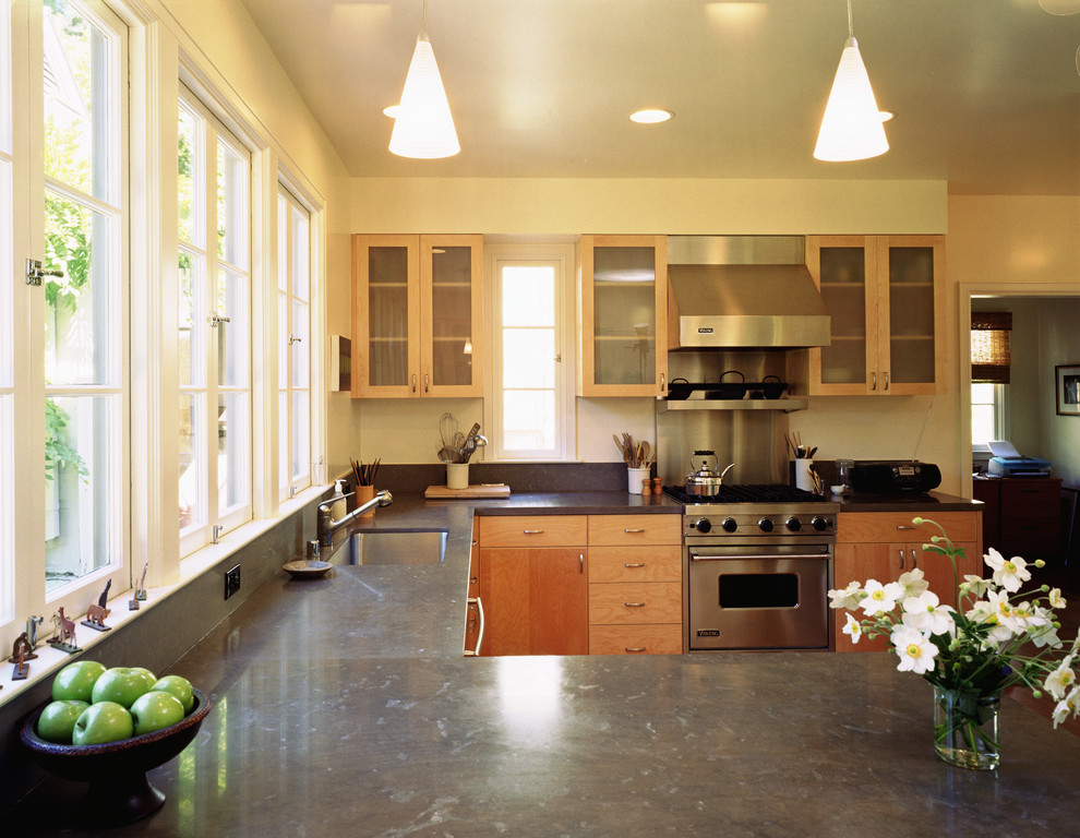 Mid-sized transitional l-shaped medium tone wood floor kitchen photo in San Francisco with an undermount sink, flat-panel cabinets, light wood cabinets, limestone countertops, stone slab backsplash, stainless steel appliances and a peninsula