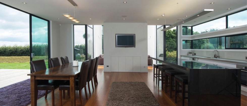This is an example of a large contemporary galley kitchen/diner in Hamilton with grey splashback, glass sheet splashback, stainless steel appliances, medium hardwood flooring and an island.