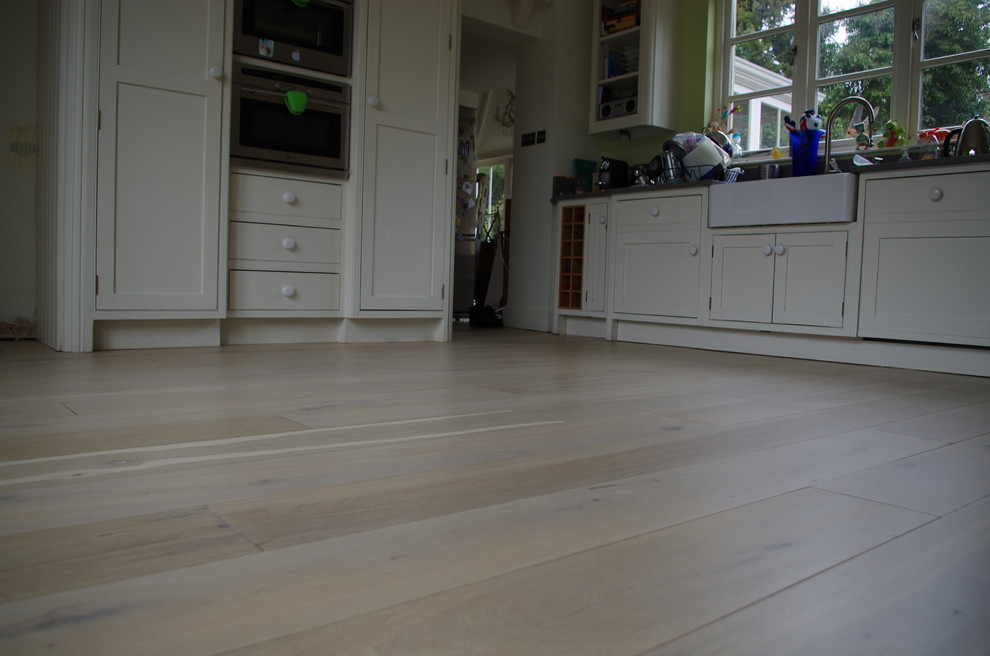 Immagine di una cucina abitabile chic di medie dimensioni con pavimento in legno verniciato
