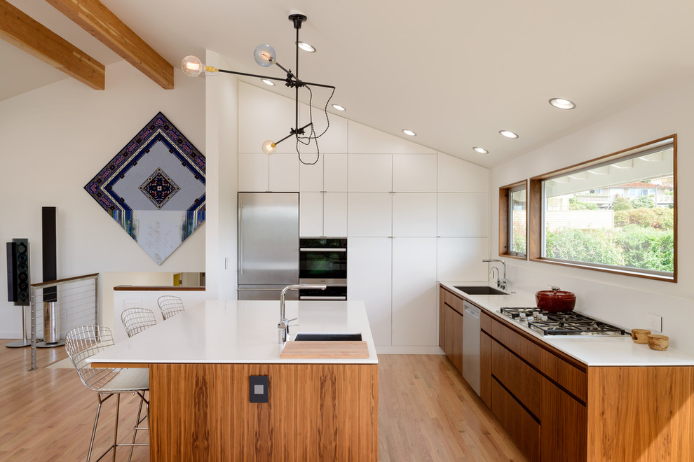 Aménagement d'une cuisine contemporaine en L et bois brun avec un évier encastré, un placard à porte plane, un électroménager en acier inoxydable, un sol en bois brun et îlot.