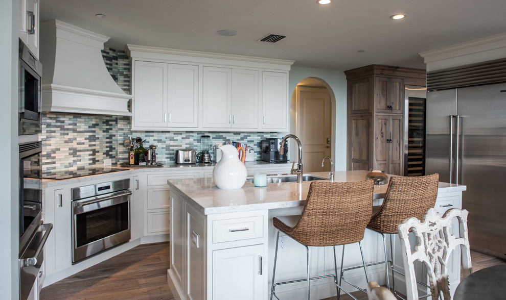 Inredning av ett modernt mellanstort kök, med en undermonterad diskho, skåp i shakerstil, vita skåp, marmorbänkskiva, flerfärgad stänkskydd, stänkskydd i stickkakel, rostfria vitvaror, mörkt trägolv och en köksö
