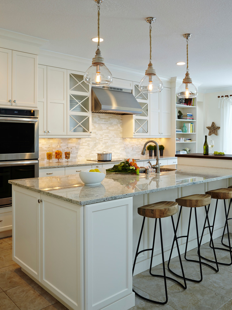 Exempel på ett klassiskt kök, med en undermonterad diskho, luckor med infälld panel, vita skåp, granitbänkskiva, beige stänkskydd, stänkskydd i stickkakel, rostfria vitvaror, klinkergolv i keramik och en köksö