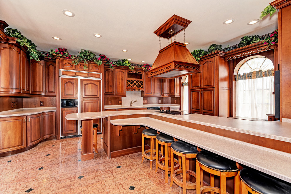 Klassisk inredning av ett beige beige kök, med luckor med upphöjd panel, skåp i mellenmörkt trä, brunt stänkskydd, stänkskydd i trä, integrerade vitvaror, en köksö och brunt golv