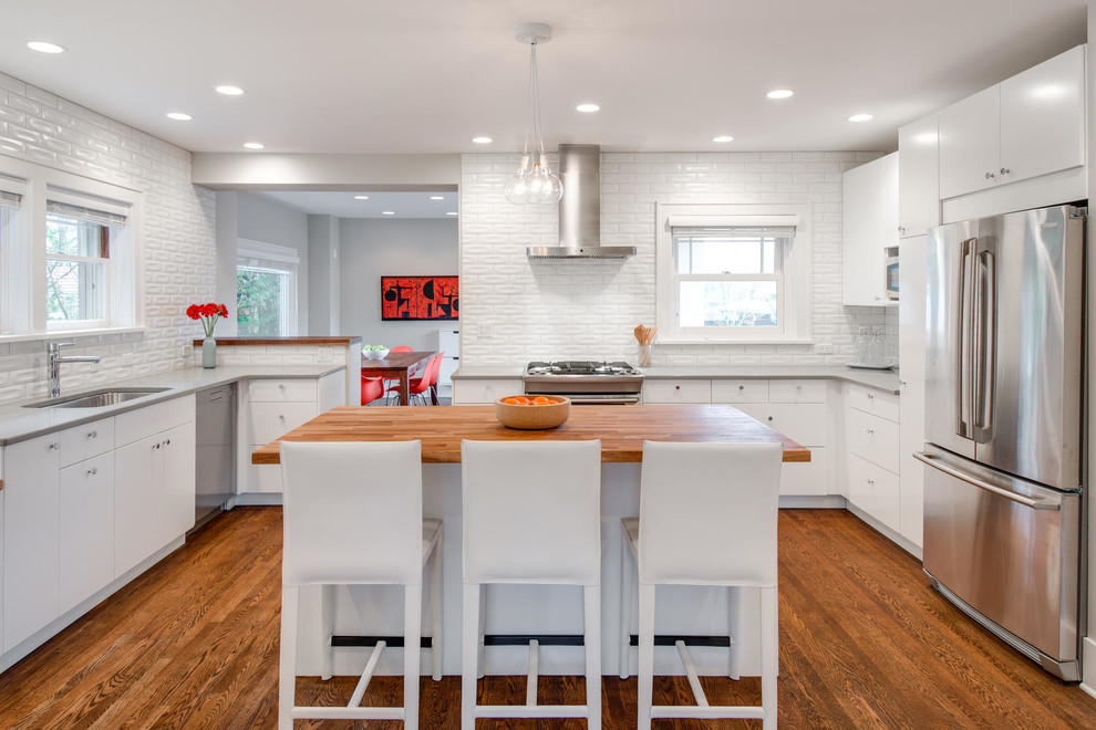 Offene Klassische Küche in U-Form mit flächenbündigen Schrankfronten, weißen Schränken, Küchenrückwand in Weiß und braunem Holzboden in Portland