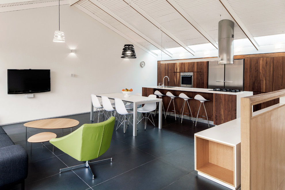 Cette image montre une cuisine ouverte parallèle minimaliste en bois brun avec un placard à porte plane et un électroménager en acier inoxydable.