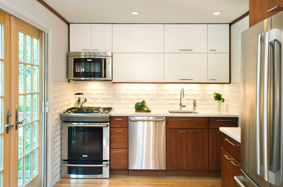Exempel på ett litet modernt l-kök, med en undermonterad diskho, släta luckor, vita skåp, vitt stänkskydd, rostfria vitvaror och ljust trägolv