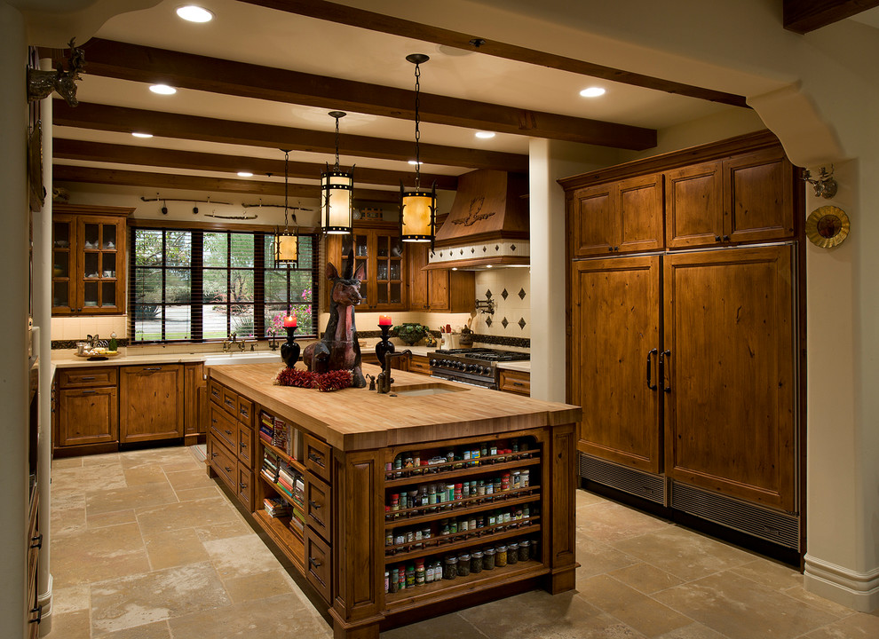 Large tuscan u-shaped limestone floor and beige floor kitchen photo in Phoenix with a farmhouse sink, recessed-panel cabinets, medium tone wood cabinets, multicolored backsplash, paneled appliances, an island, limestone backsplash and wood countertops