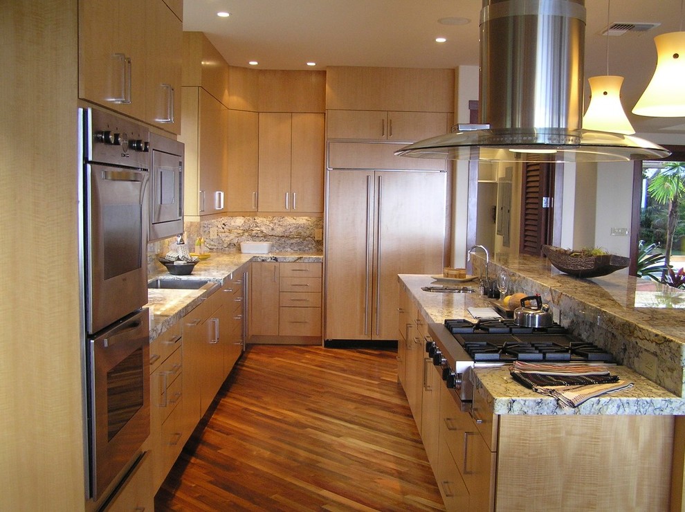 Kitchen - mid-sized tropical l-shaped medium tone wood floor kitchen idea in Hawaii with an undermount sink, flat-panel cabinets, light wood cabinets, granite countertops, white backsplash, stone slab backsplash, stainless steel appliances and an island