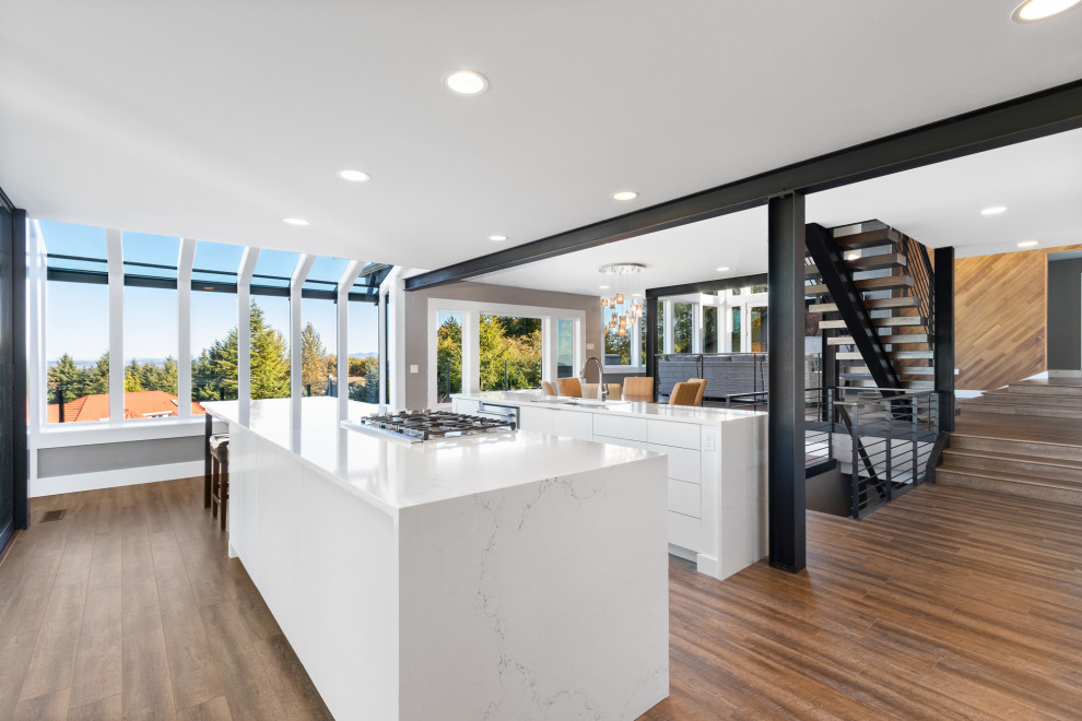 Inspiration for a large modern galley kitchen/diner in Seattle with flat-panel cabinets, white cabinets, quartz worktops, multiple islands, white worktops, a submerged sink, stainless steel appliances, dark hardwood flooring and brown floors.