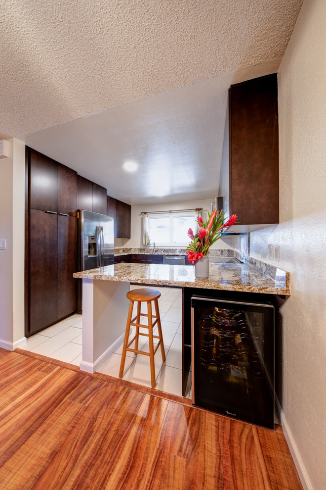 Small modern u-shaped enclosed kitchen in Hawaii with a single-bowl sink, flat-panel cabinets, dark wood cabinets, granite worktops, stainless steel appliances, ceramic flooring, no island, beige floors and yellow worktops.