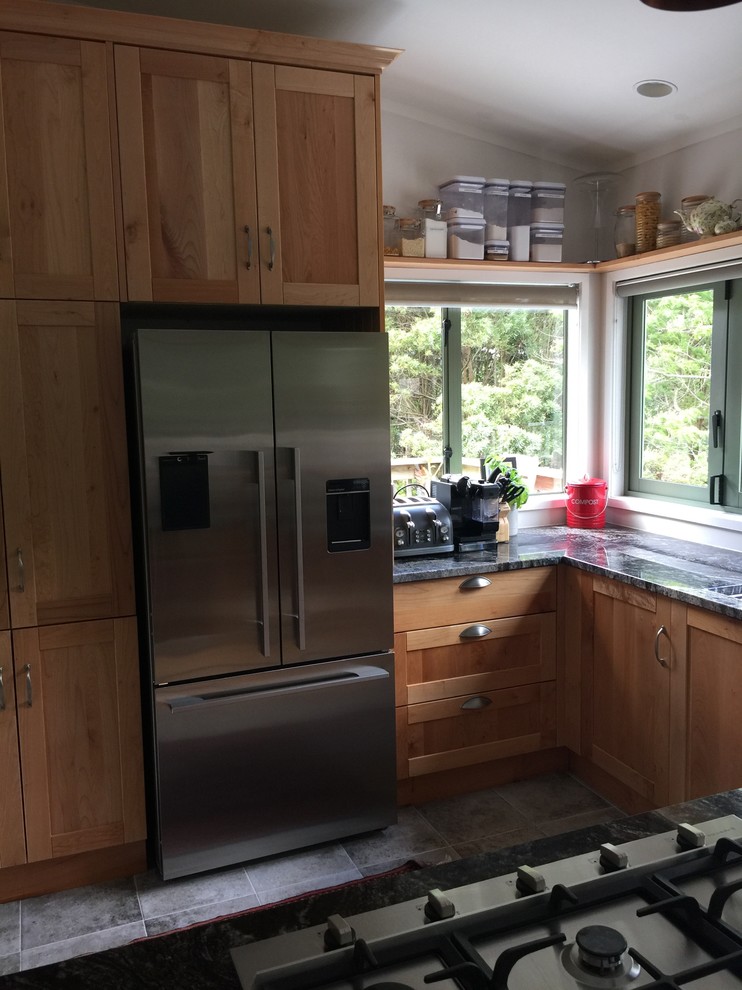 Photo of a medium sized farmhouse kitchen/diner in Auckland with a submerged sink, shaker cabinets, medium wood cabinets, granite worktops, stainless steel appliances, porcelain flooring and an island.