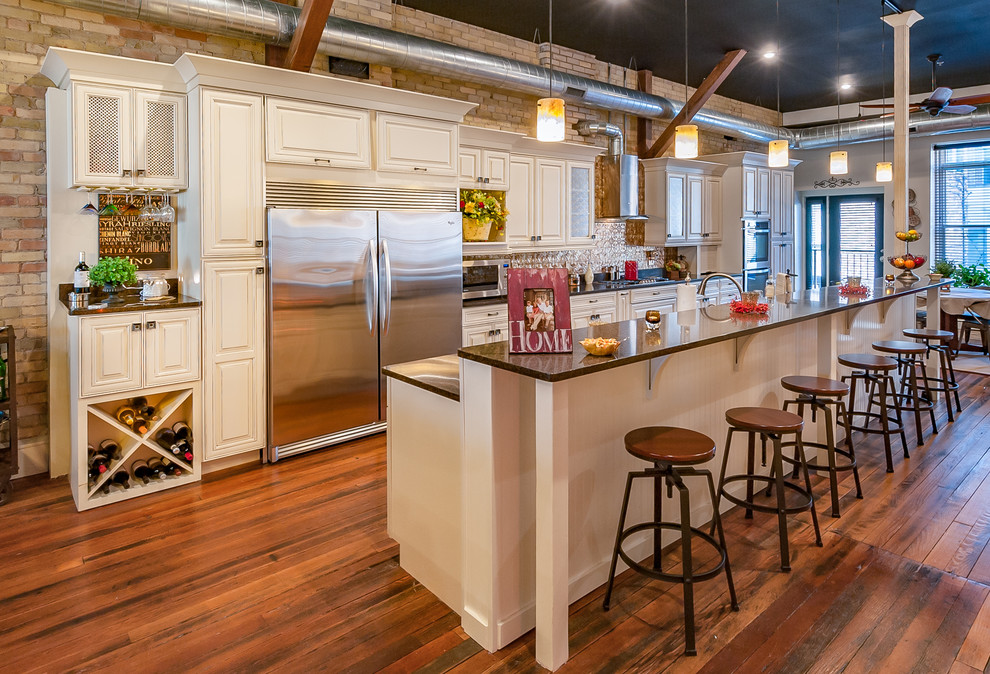 グランドラピッズにあるインダストリアルスタイルのおしゃれなキッチン (レイズドパネル扉のキャビネット、白いキャビネット、シルバーの調理設備、無垢フローリング) の写真