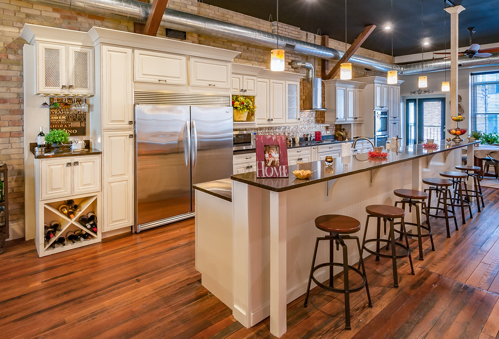 Ejemplo de cocina industrial abierta con armarios con paneles con relieve, puertas de armario blancas, electrodomésticos de acero inoxidable, suelo de madera en tonos medios, una isla y barras de cocina