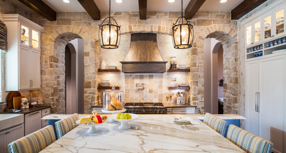 This is an example of a medium sized rustic galley kitchen/diner in Houston with a belfast sink, shaker cabinets, white cabinets, beige splashback, ceramic splashback, integrated appliances, an island and beige worktops.