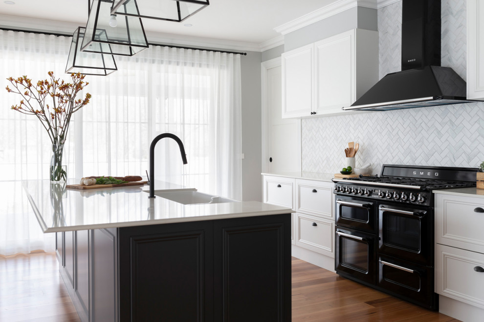 キャンベラにある中くらいなトラディショナルスタイルのおしゃれなキッチン (エプロンフロントシンク、シェーカースタイル扉のキャビネット、青いキャビネット、クオーツストーンカウンター、白いキッチンパネル、モザイクタイルのキッチンパネル、黒い調理設備、淡色無垢フローリング、白いキッチンカウンター) の写真