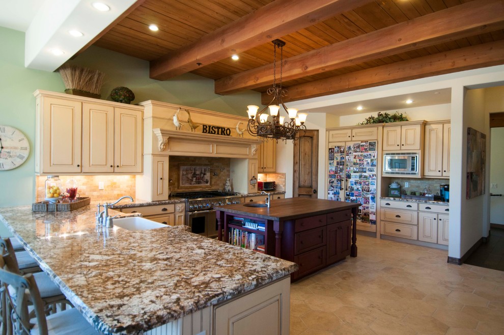 Foto på ett stort rustikt kök, med luckor med upphöjd panel, beige skåp, granitbänkskiva, beige stänkskydd, stänkskydd i mosaik, rostfria vitvaror, kalkstensgolv och en köksö