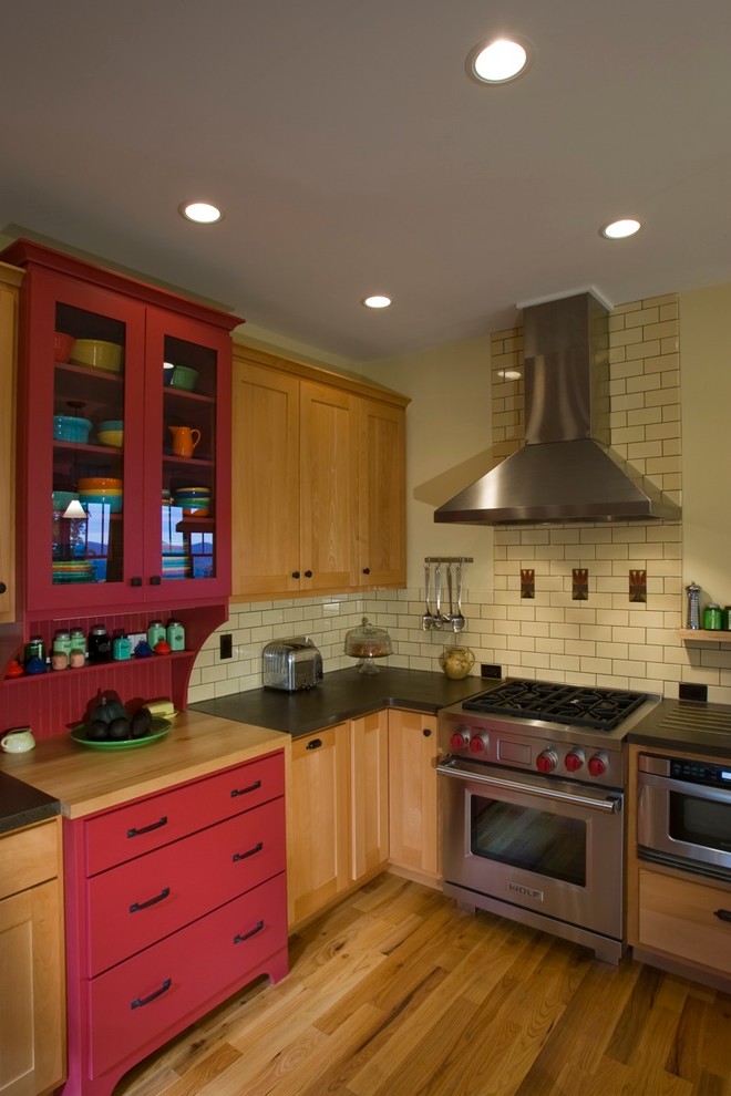 На фото: кухня в классическом стиле с фартуком из плитки кабанчик, столешницей из бетона, красными фасадами и техникой из нержавеющей стали с