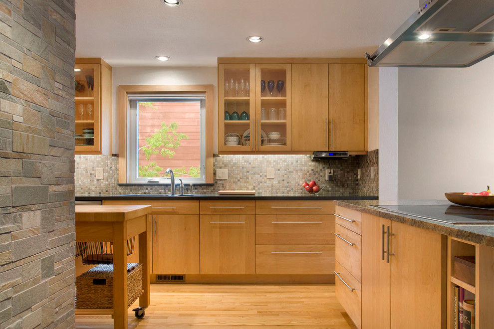 Foto på ett mellanstort funkis kök, med en undermonterad diskho, släta luckor, skåp i ljust trä, granitbänkskiva, flerfärgad stänkskydd, stänkskydd i stenkakel, rostfria vitvaror, ljust trägolv och en köksö