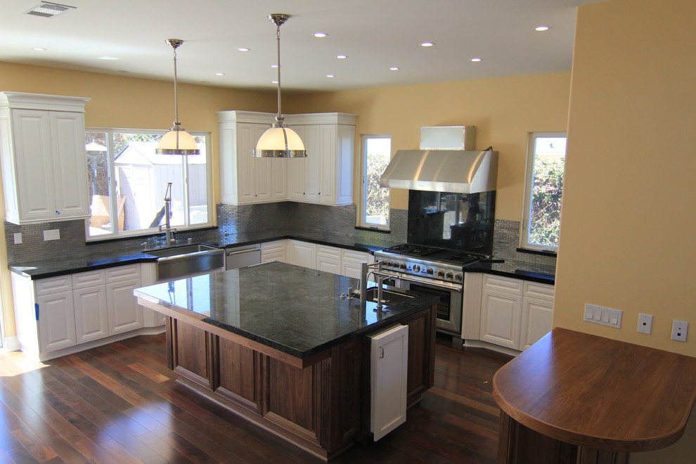 Idéer för att renovera ett stort vintage kök, med en undermonterad diskho, luckor med upphöjd panel, vita skåp, granitbänkskiva, stänkskydd med metallisk yta, stänkskydd i metallkakel, rostfria vitvaror, mörkt trägolv, en köksö och brunt golv