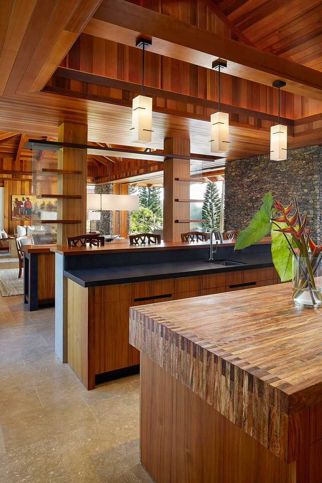 Large world-inspired open plan kitchen in Hawaii with a double-bowl sink, flat-panel cabinets, medium wood cabinets, wood worktops, multiple islands and stainless steel appliances.