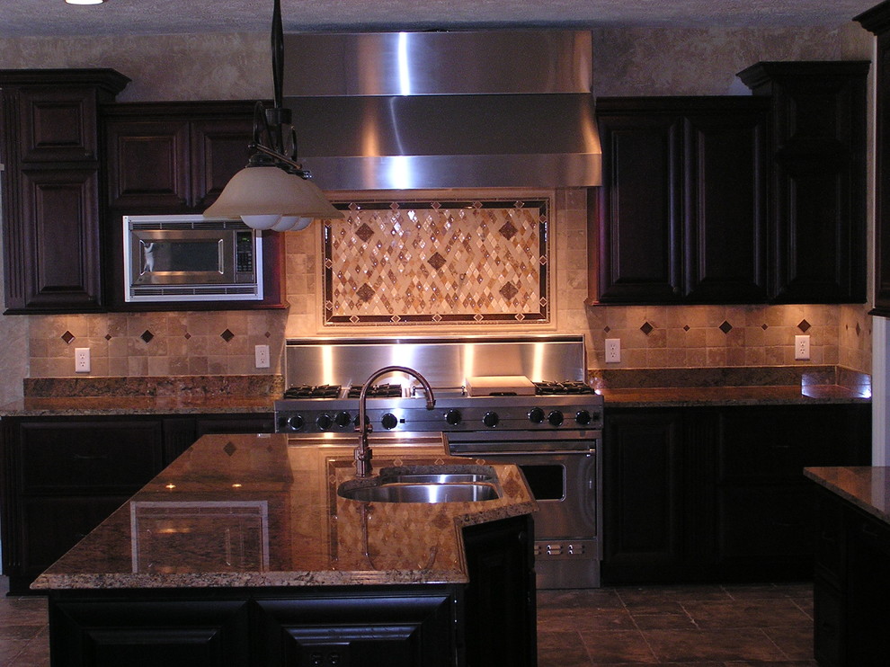 クリーブランドにある高級なラスティックスタイルのおしゃれなキッチン (赤いキャビネット、御影石カウンター、茶色いキッチンパネル、トラバーチンのキッチンパネル、シルバーの調理設備、磁器タイルの床、茶色い床、茶色いキッチンカウンター) の写真