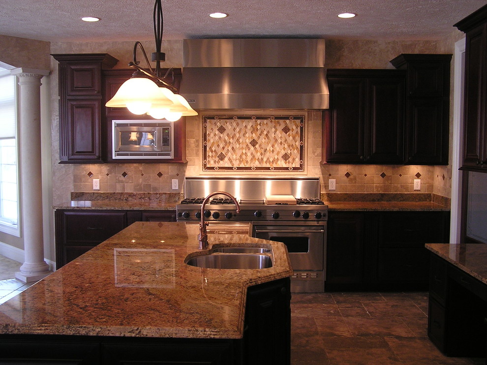Rustik inredning av ett brun brunt kök, med röda skåp, granitbänkskiva, brunt stänkskydd, stänkskydd i travertin, rostfria vitvaror, klinkergolv i porslin, en köksö och brunt golv
