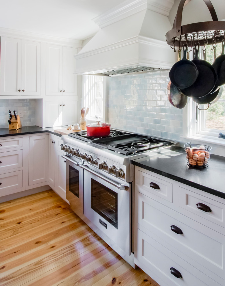Medium sized traditional l-shaped open plan kitchen in Boston with a submerged sink, shaker cabinets, white cabinets, granite worktops, blue splashback, porcelain splashback, stainless steel appliances, light hardwood flooring and an island.