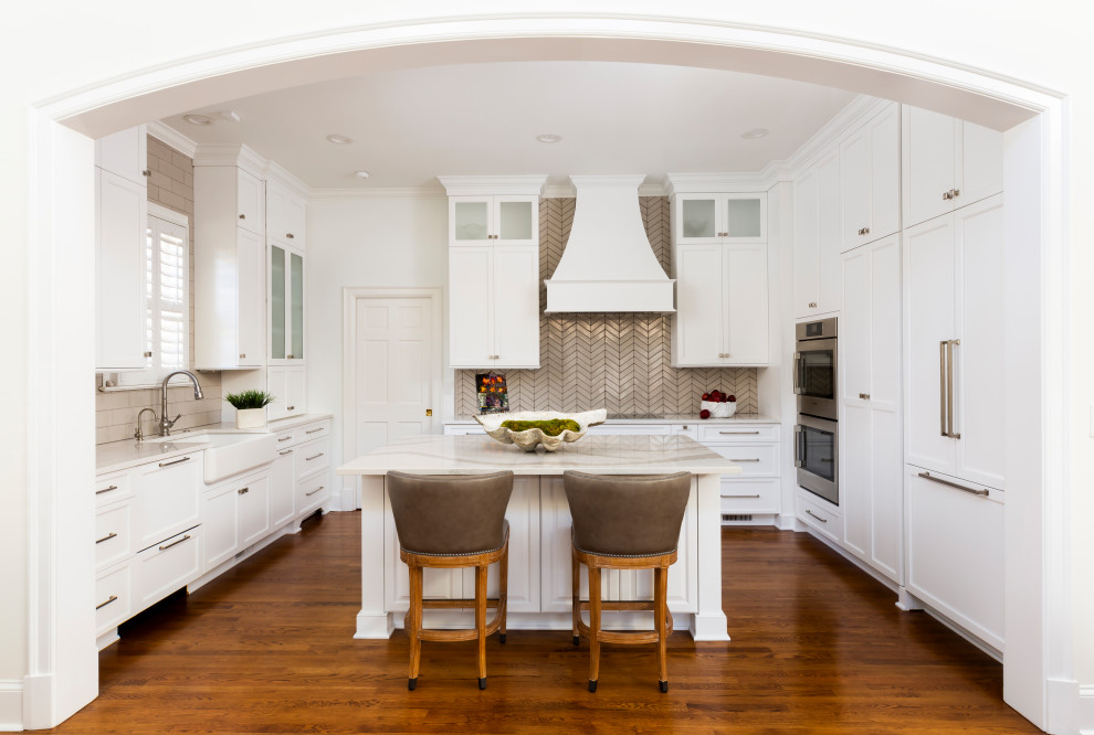 シャーロットにある高級な広いトラディショナルスタイルのおしゃれなアイランドキッチン (エプロンフロントシンク、レイズドパネル扉のキャビネット、白いキャビネット、白いキッチンパネル、モザイクタイルのキッチンパネル、シルバーの調理設備、淡色無垢フローリング、ベージュの床、緑のキッチンカウンター) の写真