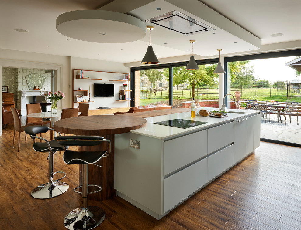 Design ideas for a medium sized contemporary open plan kitchen in Buckinghamshire with a submerged sink, flat-panel cabinets, dark hardwood flooring, an island, brown floors, beige worktops and white cabinets.