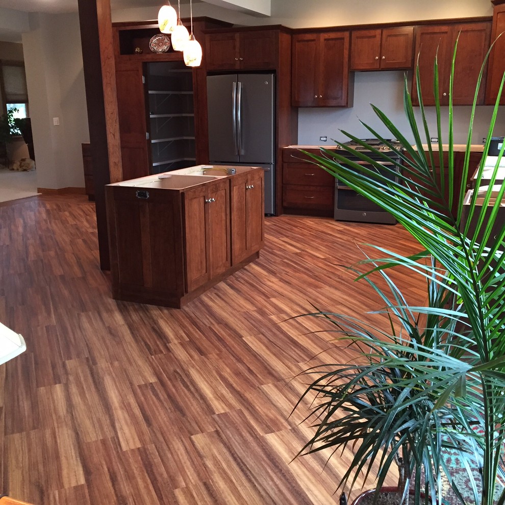 Inspiration for a traditional l-shaped kitchen/diner in Chicago with an island, stainless steel appliances, vinyl flooring, recessed-panel cabinets and dark wood cabinets.