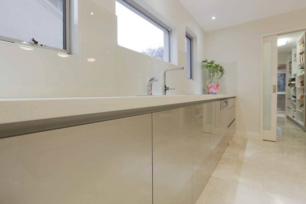 Inspiration for an expansive contemporary galley kitchen in Perth with a double-bowl sink, flat-panel cabinets, marble worktops, white splashback, glass sheet splashback, stainless steel appliances, travertine flooring and an island.