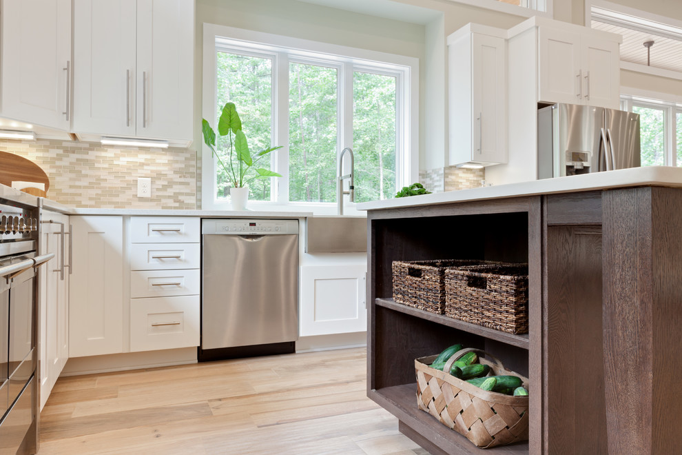 Réalisation d'une très grande cuisine américaine design en U avec un évier de ferme, un placard à porte shaker, des portes de placard blanches, un plan de travail en quartz modifié, une crédence beige, une crédence en carreau de verre, un électroménager en acier inoxydable, un sol en carrelage de porcelaine, îlot, un sol beige et un plan de travail blanc.