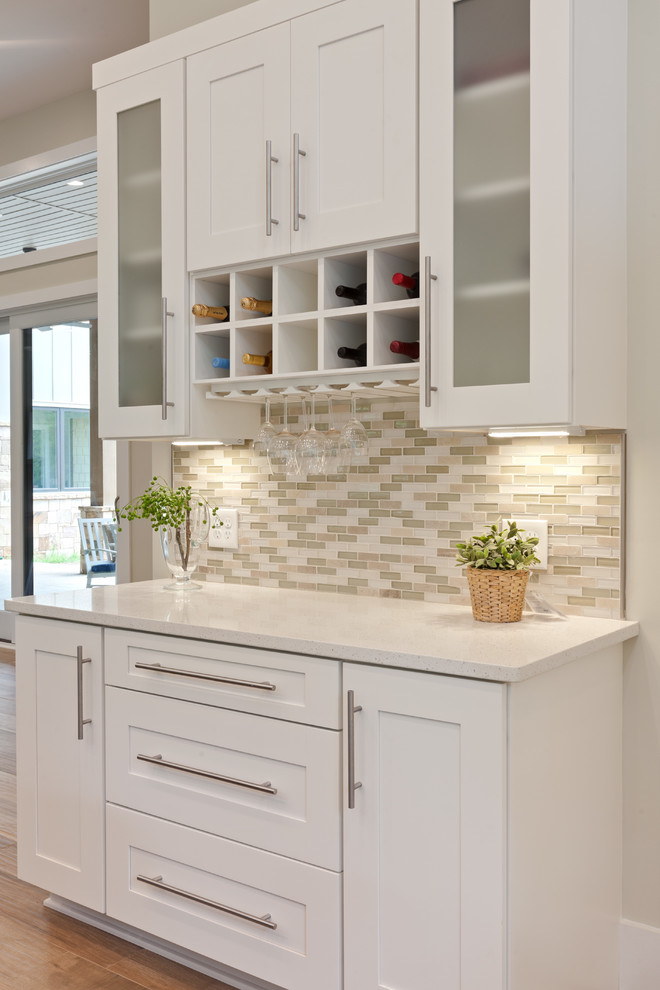 Inspiration for an expansive contemporary u-shaped kitchen/diner in Atlanta with a belfast sink, shaker cabinets, white cabinets, engineered stone countertops, beige splashback, glass tiled splashback, stainless steel appliances, porcelain flooring, an island, beige floors and white worktops.
