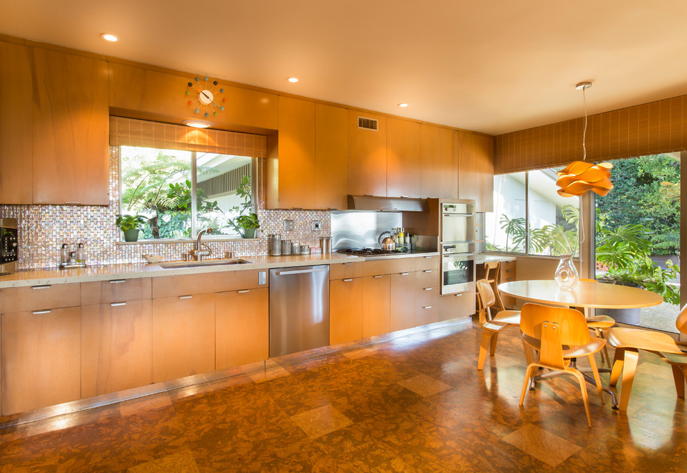 Design ideas for a large contemporary galley kitchen/diner in Santa Barbara with a built-in sink, flat-panel cabinets, medium wood cabinets, composite countertops, beige splashback, metal splashback, stainless steel appliances, laminate floors, no island and brown floors.
