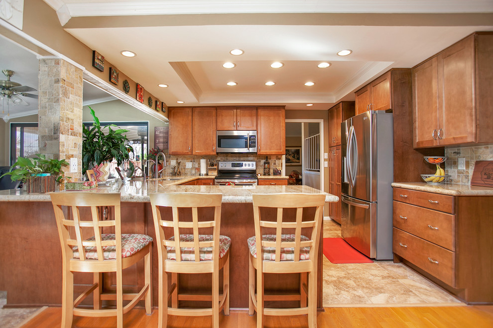 Exempel på ett mellanstort klassiskt kök, med en enkel diskho, luckor med infälld panel, skåp i mellenmörkt trä, granitbänkskiva, flerfärgad stänkskydd, stänkskydd i travertin, rostfria vitvaror, klinkergolv i porslin, en halv köksö och flerfärgat golv