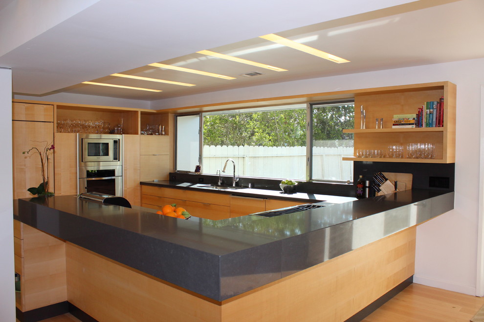 Bild på ett mellanstort funkis kök, med en dubbel diskho, släta luckor, skåp i ljust trä, bänkskiva i kvarts, fönster som stänkskydd, integrerade vitvaror, ljust trägolv, en halv köksö och beiget golv