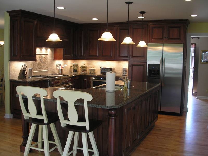 Modern inredning av ett stort kök, med en dubbel diskho, luckor med upphöjd panel, skåp i mörkt trä, granitbänkskiva, rostfria vitvaror, mellanmörkt trägolv och flera köksöar
