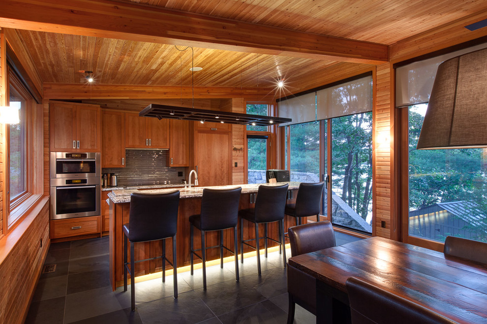 Exemple d'une cuisine américaine montagne en bois brun avec un placard à porte shaker, une crédence grise, un électroménager en acier inoxydable et îlot.