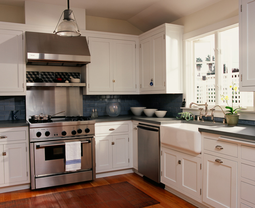 На фото: кухня в классическом стиле с техникой из нержавеющей стали, с полувстраиваемой мойкой (с передним бортиком), фасадами в стиле шейкер, белыми фасадами, синим фартуком и фартуком из плитки кабанчик