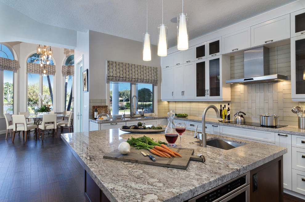 Eat-in kitchen - large transitional galley dark wood floor eat-in kitchen idea in Miami with a drop-in sink, recessed-panel cabinets, white cabinets, granite countertops, gray backsplash, glass tile backsplash, stainless steel appliances and an island
