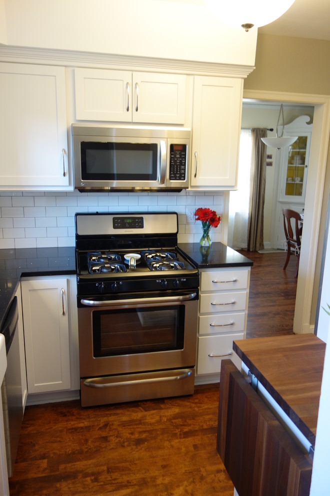 Bild på ett avskilt, litet vintage l-kök, med en rustik diskho, skåp i shakerstil, vita skåp, bänkskiva i kvarts, vitt stänkskydd, stänkskydd i keramik, rostfria vitvaror, mörkt trägolv och brunt golv