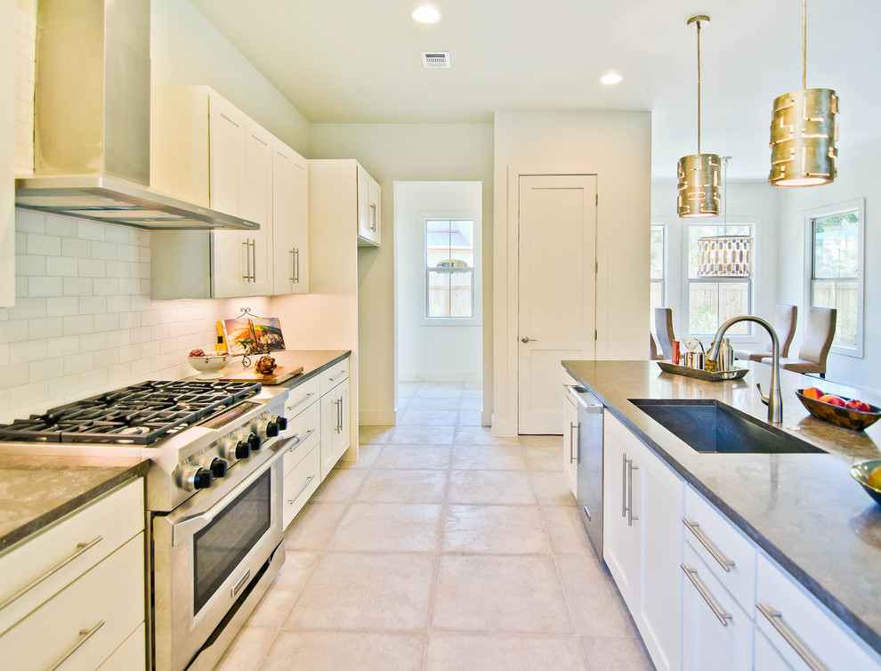 Example of a minimalist kitchen design in Austin with stainless steel appliances, subway tile backsplash and limestone countertops