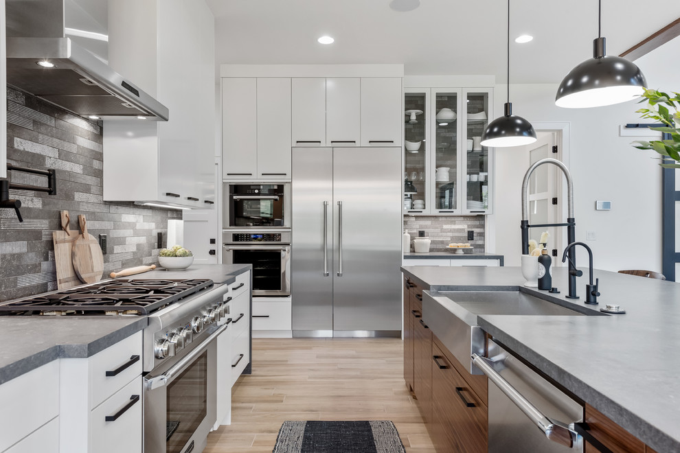 Inredning av ett modernt stort grå grått kök, med en rustik diskho, släta luckor, vita skåp, bänkskiva i kvartsit, grått stänkskydd, stänkskydd i stenkakel, rostfria vitvaror, klinkergolv i porslin, en köksö och beiget golv